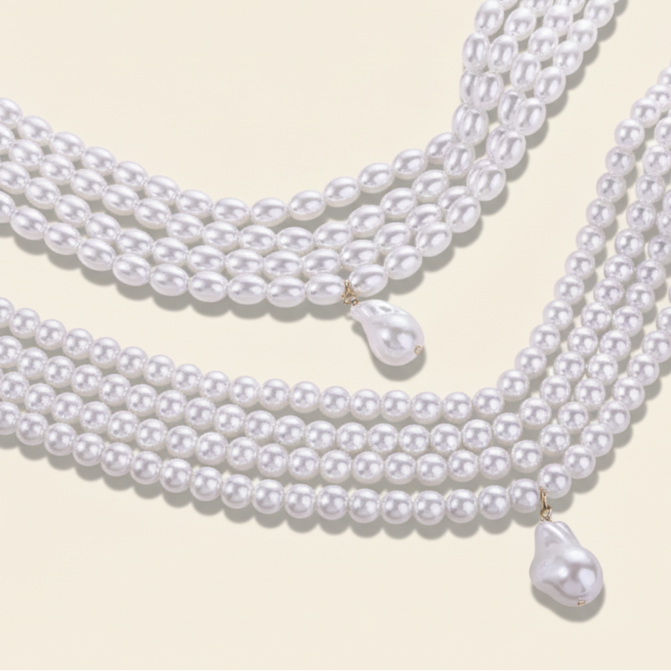 A close-up of a multi-strand white pearl necklace with two large baroque pearl drop pendants.