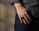 Gentle man wearing a SteelForce Black Ring for men - 316L stainless steel band on a blurred background