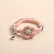 Pink pet collar with a knitted flower and bell on a beige background
