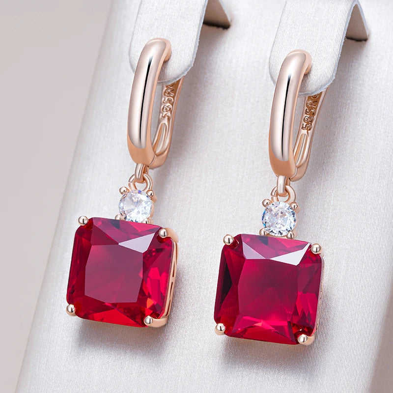 Rose gold earrings with red gemstones on a white background