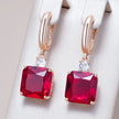 Rose gold earrings with red gemstones on a white background