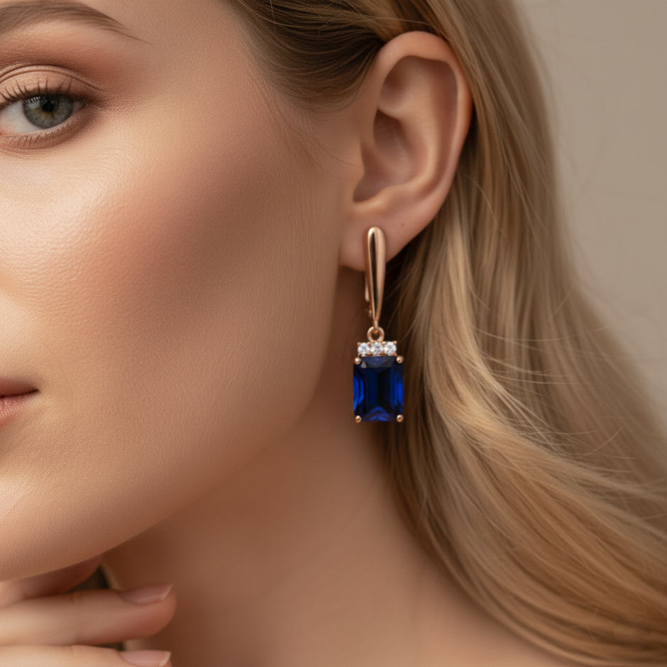 Close-up of a woman wearing a blue gemstone earring with a neutral background