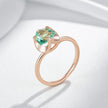 Rose gold ring with a green gemstone on a light gray background