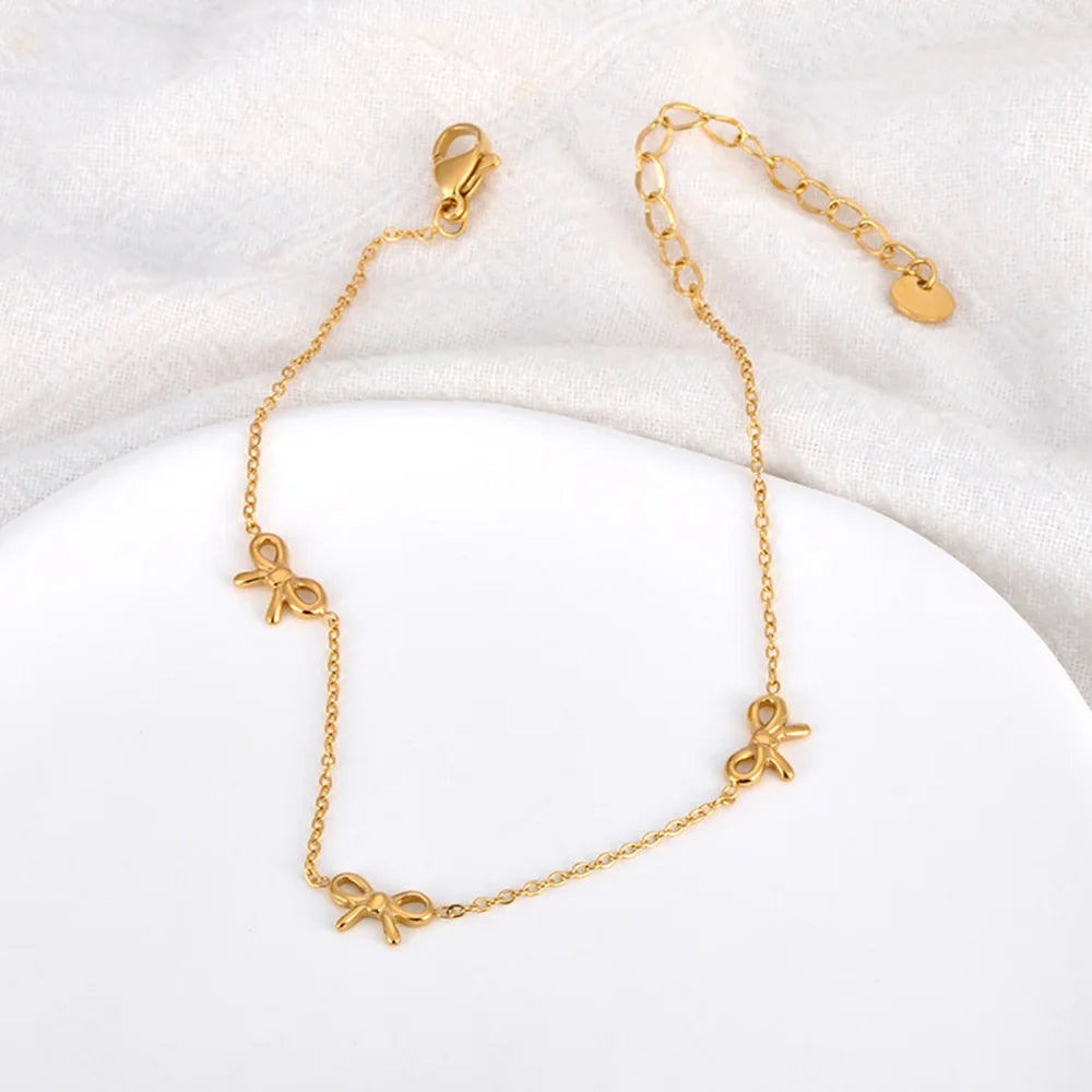 Gold anklet with bow charms on a white background