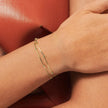 Gold bracelet on a wrist with a red leather surface