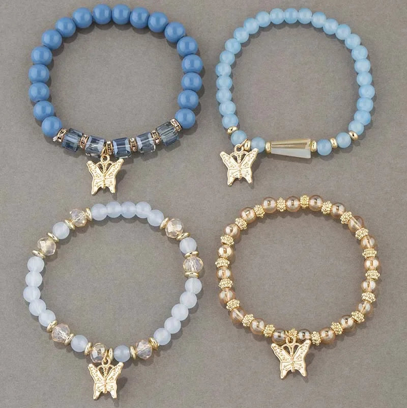 Four beaded bracelets with butterfly charms on a gray background