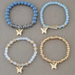 Four beaded bracelets with butterfly charms on a gray background
