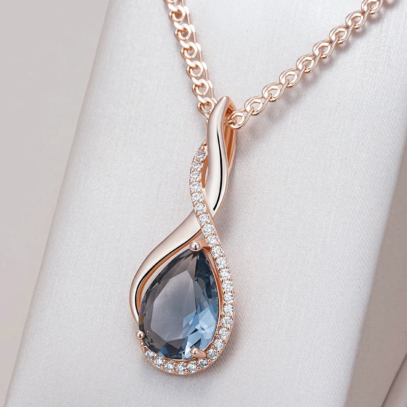 Rose gold necklace with a blue teardrop pendant on a white background