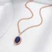 Rose gold necklace with a blue gemstone pendant on a white background