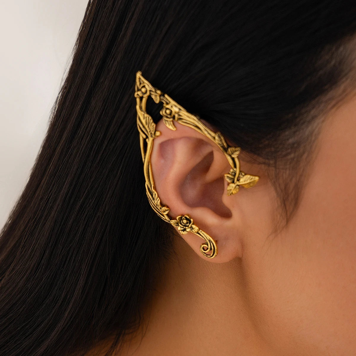 Gold ornate ear cuff worn by a person with dark hair.