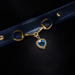 Blue leather strap with a gold clasp and blue heart charm on a black background