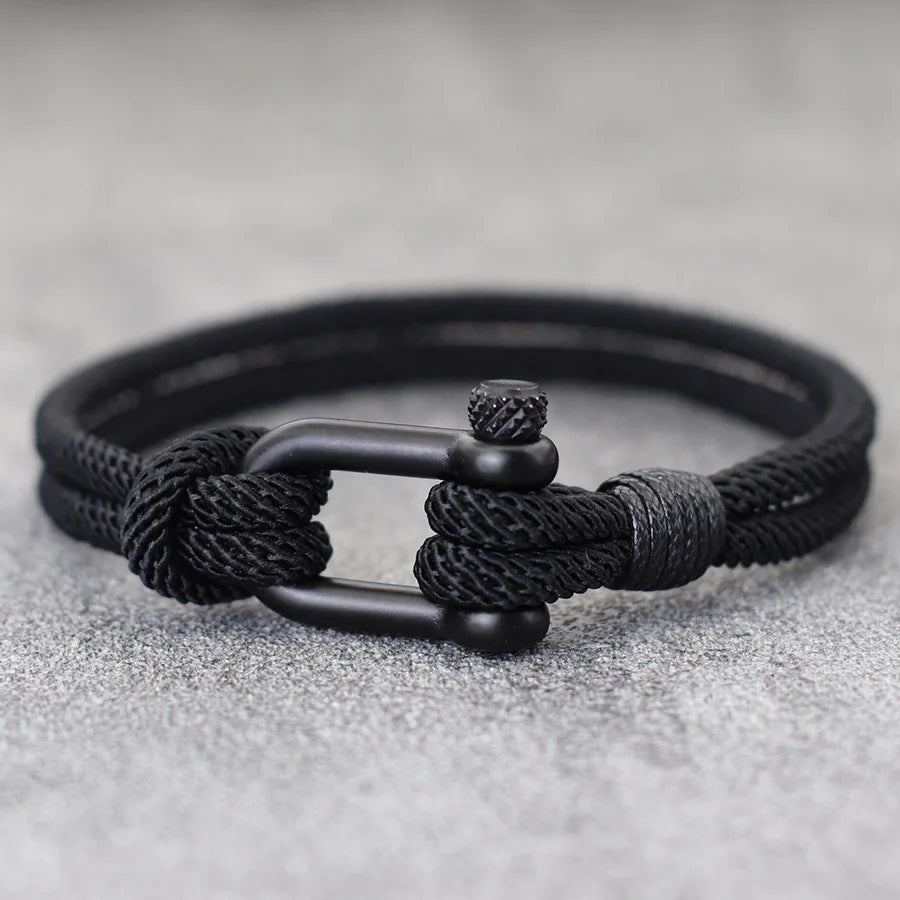 Black braided bracelet with a metal clasp on a gray background