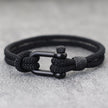 Black braided bracelet with a metal clasp on a gray background