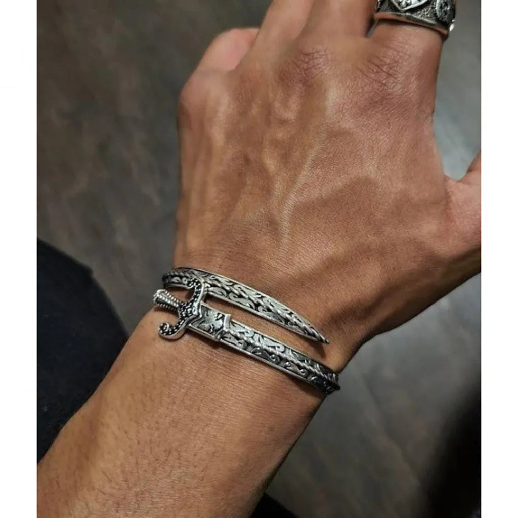 Silver bracelet on a wrist with a neutral background