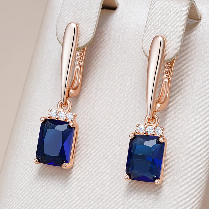 Rose gold earrings with blue gemstones on a beige background