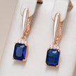 Rose gold earrings with blue gemstones on a beige background