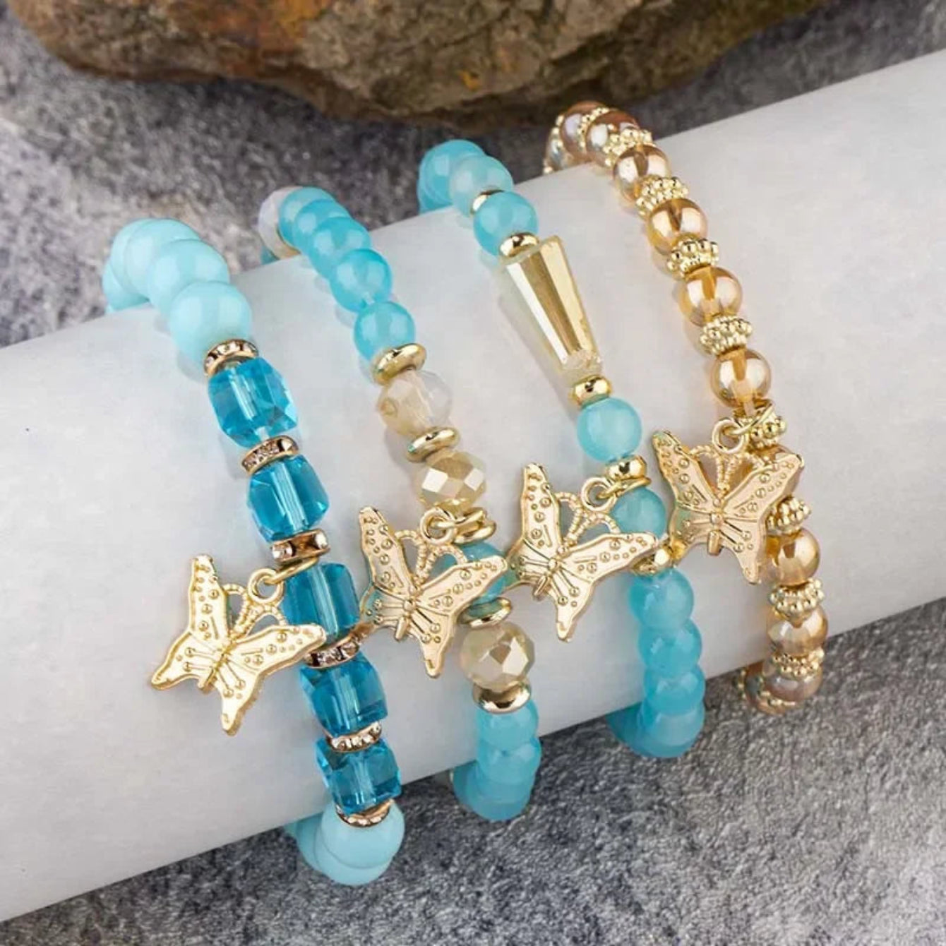 Turquoise beaded bracelet with gold butterfly charms on a white surface.