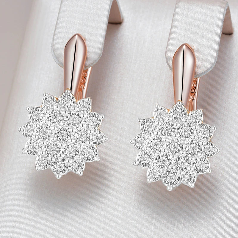 Rose gold earrings with diamond-like stones on a light gray background