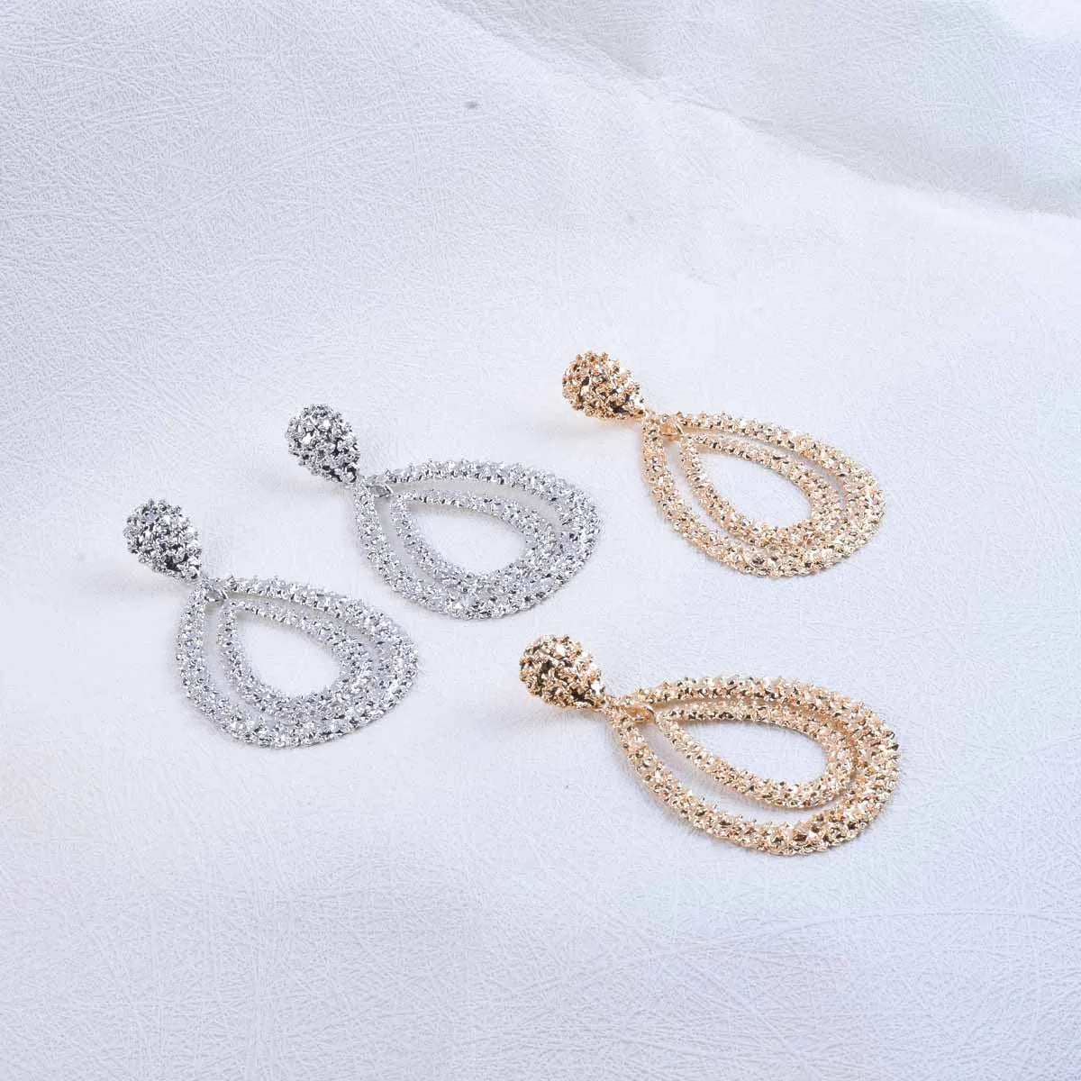 Pair of silver and gold earrings on a light gray background