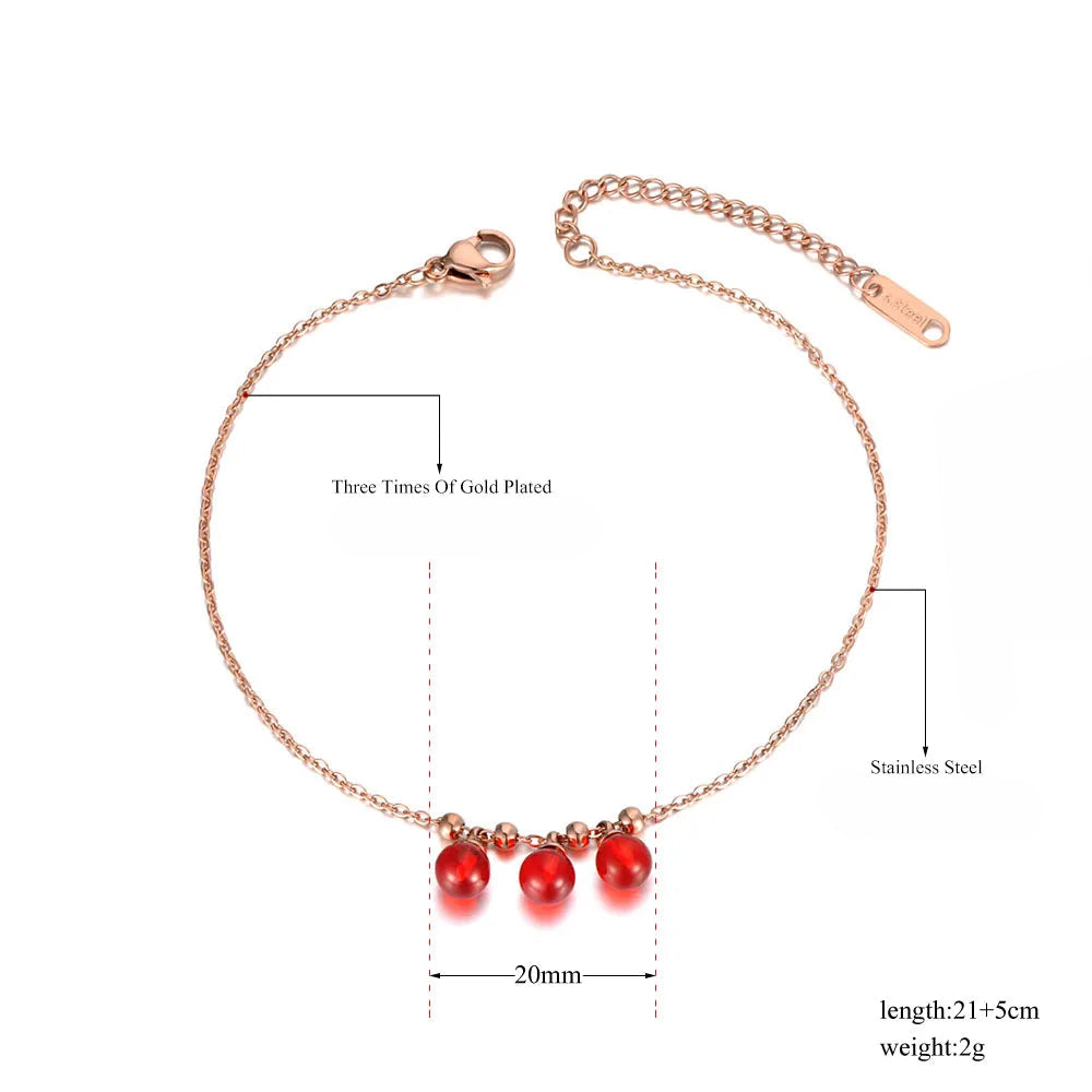 Rose gold anklet with red beads on a white background