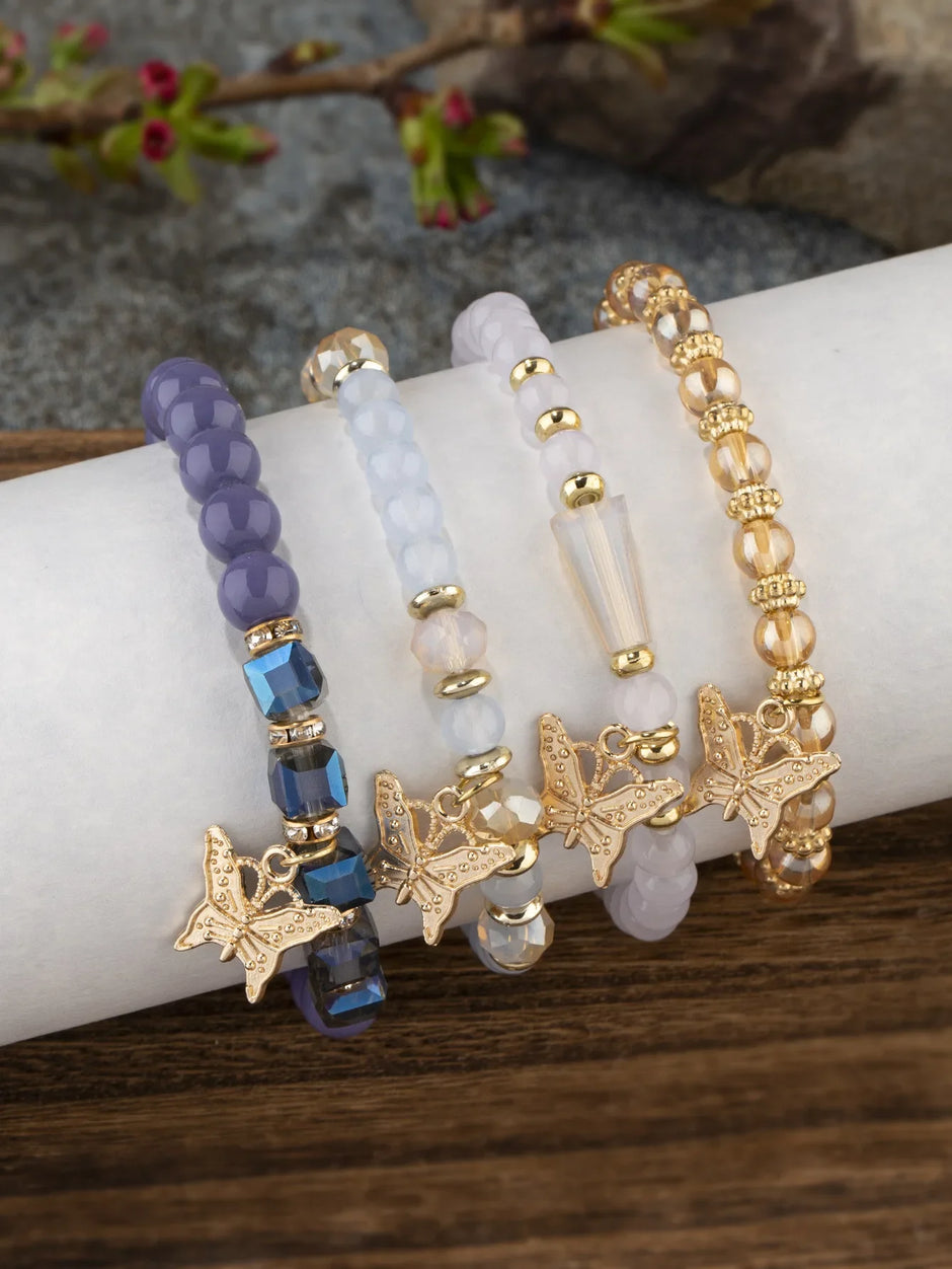 four beaded bracelets with starfish charms on a wrist against a natural background.