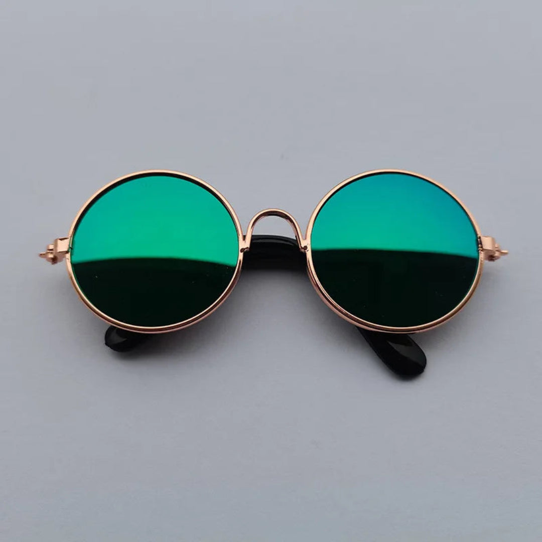 Round sunglasses with green lenses and gold frame on a gray background