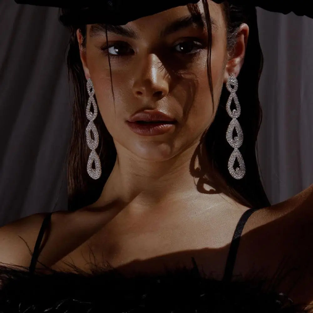 Woman wearing large diamond earrings with a dark background