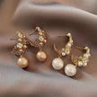Pair of gold and pearl earrings on a soft fabric background