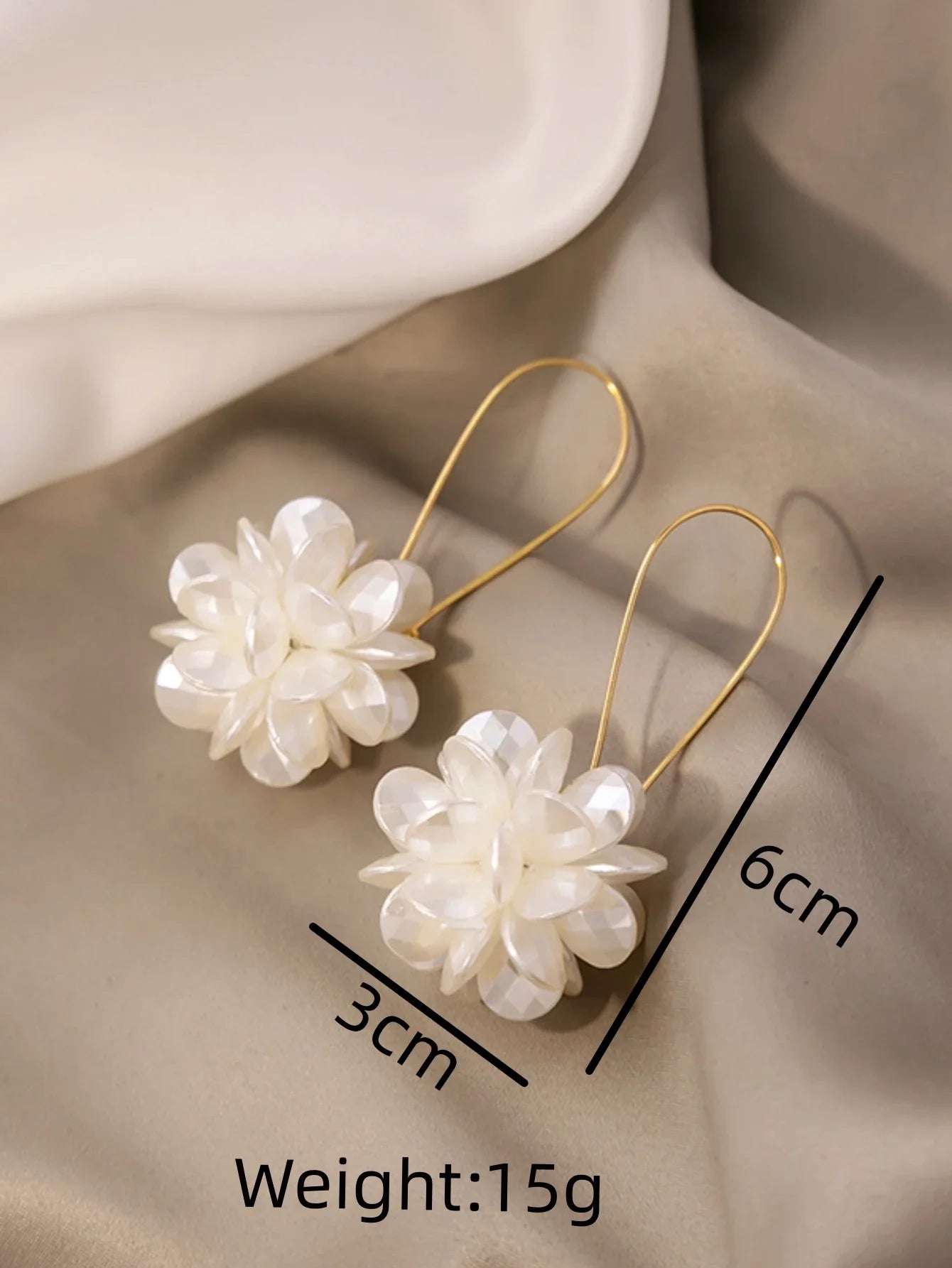 Floral earrings with measurements and weight on a beige fabric background