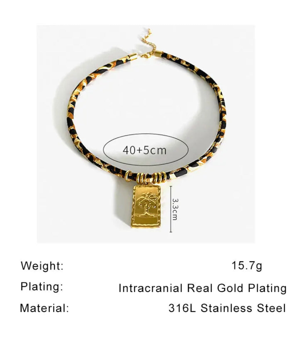 Necklace with gold and black pattern on a white background, featuring product information text.