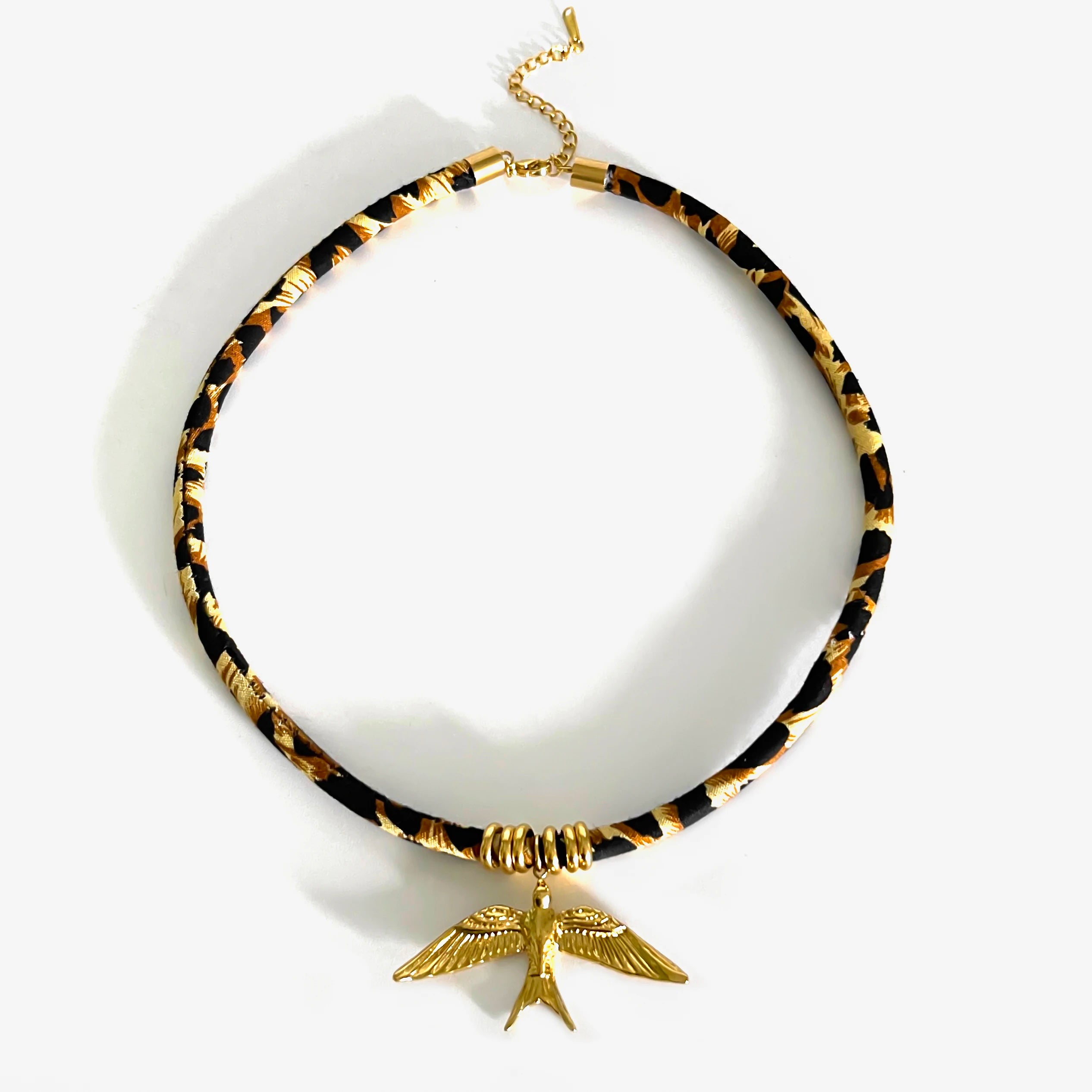 Necklace with tortoiseshell pattern and gold bird pendant on a white background