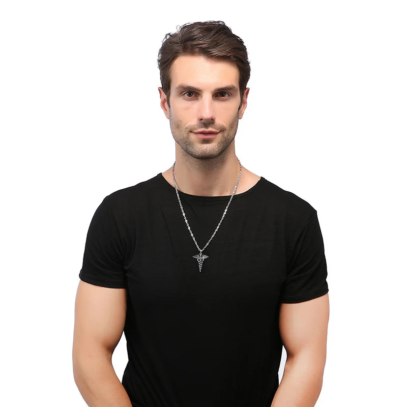 A man wearing a black t-shirt and a silver necklace with a caduceus pendant with a white background