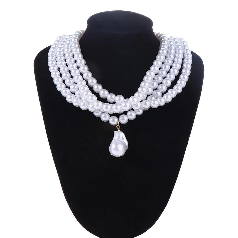 a choker-style necklace made of four rows of small, round white pearls. It has a gold-toned clasp at the back and a single, larger, teardrop-shaped white pearl pendant hanging from the center front, on a black mannequin bust with a white background