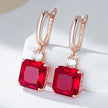 Rose gold earrings with red gemstones on a white background