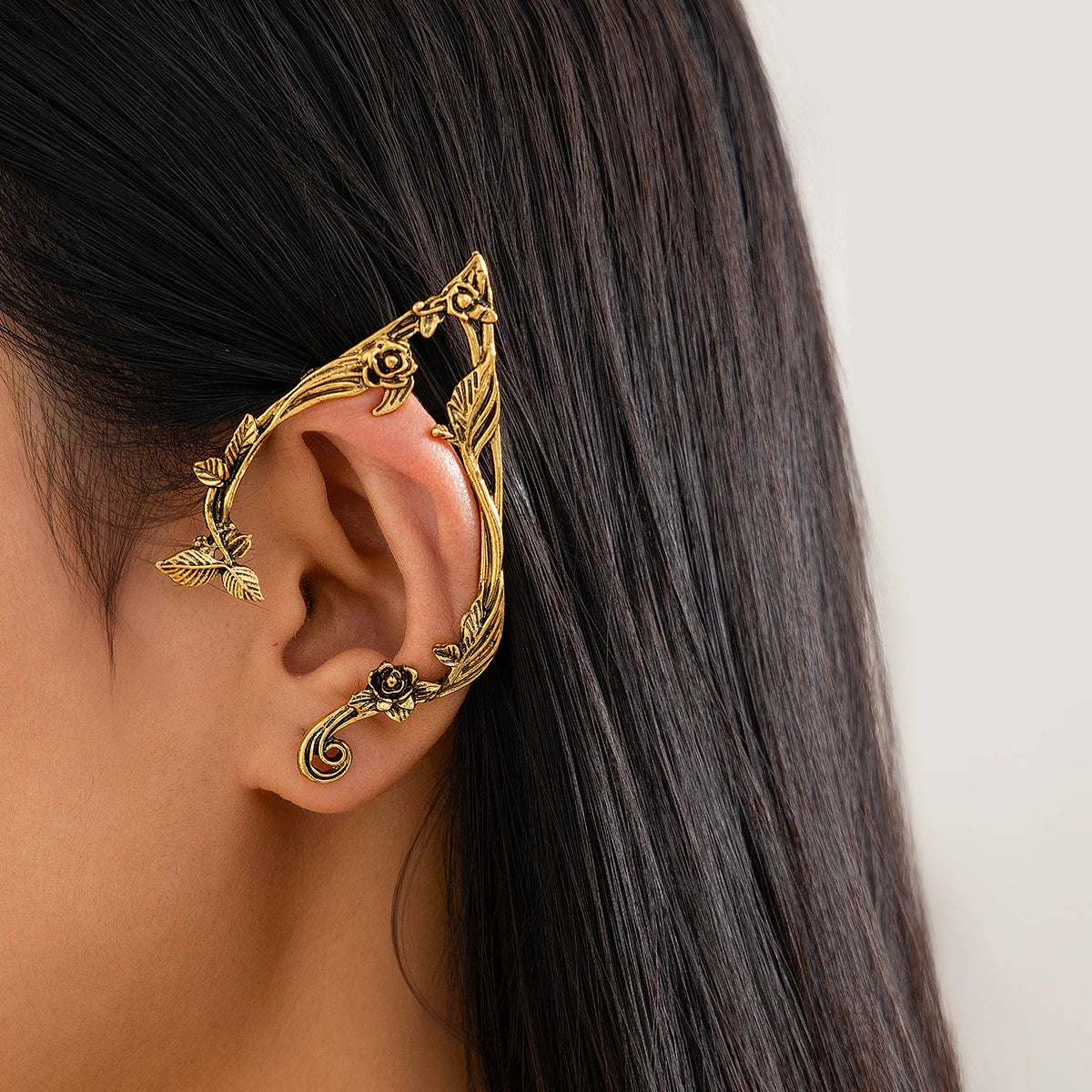Gold elvish ear cuff worn by a person with long dark hair on a plain background