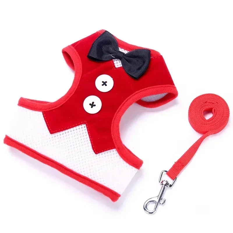 Red dog harness with black bow tie and white buttons, accompanied by a matching leash on a white background.