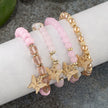 Set of pink beaded bracelets with gold butterfly charms on a wrist.