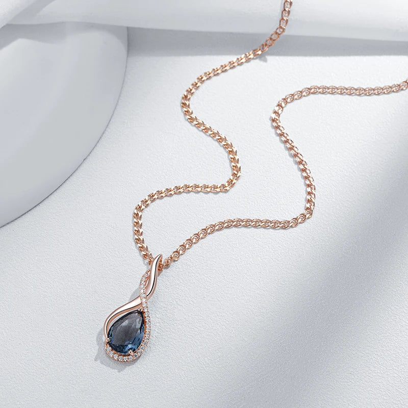 Rose gold necklace with a blue teardrop pendant on a white background