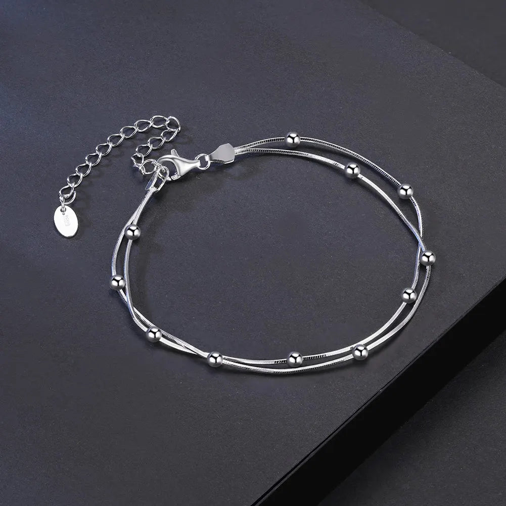 Silver bracelet with beaded design on a dark surface