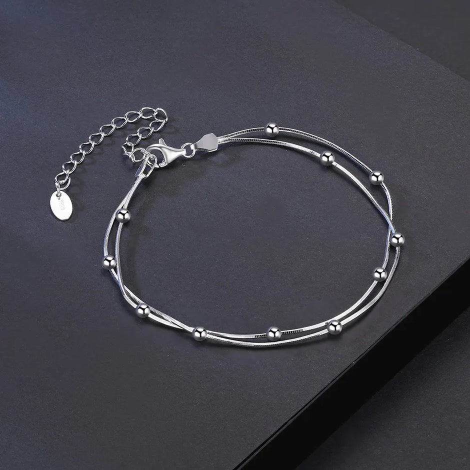 Silver bracelet with beaded design on a dark surface
