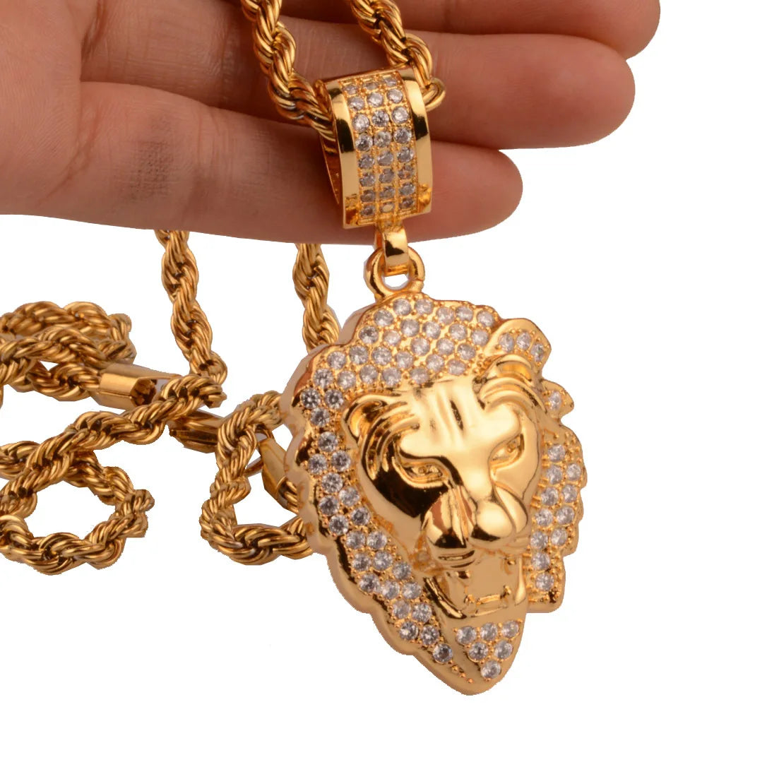 Gold lion pendant necklace held by a hand on a white background