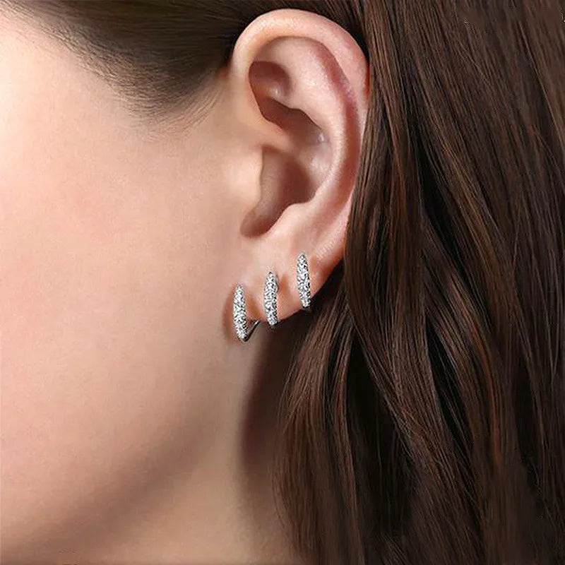 Close-up of an ear wearing silver stud earrings with a blurred background