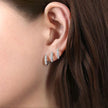 Close-up of an ear wearing silver stud earrings with a blurred background