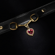 Black leather strap with gold hardware and a red heart charm on a black background