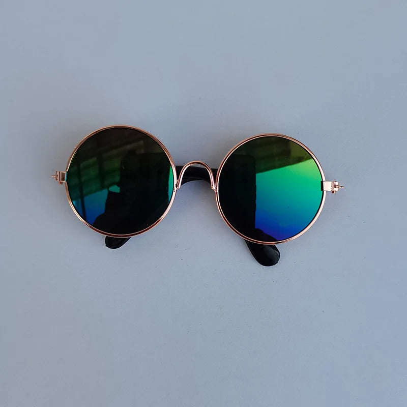 Round sunglasses with rose gold frame and green-tinted lenses on a light blue background