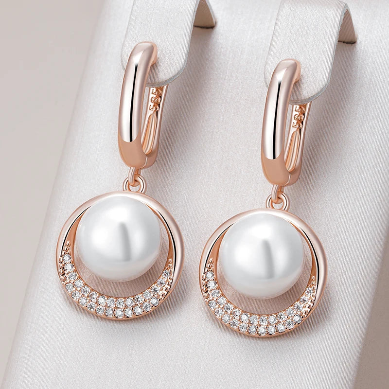 Rose gold earrings with pearls and small diamonds on a light fabric background
