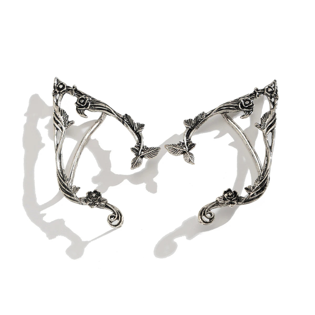 Pair of silver elf ears with intricate designs on a white background