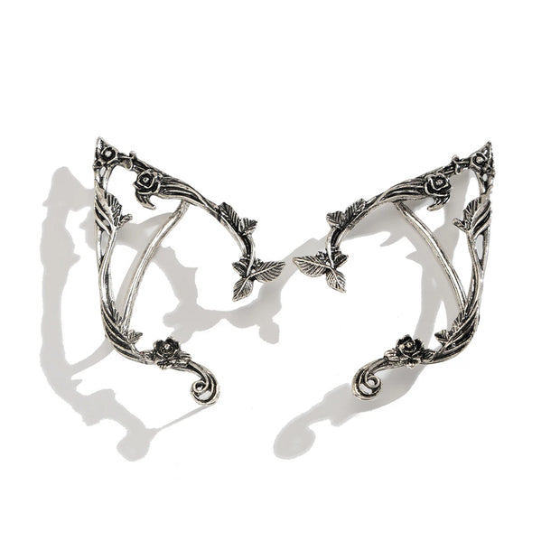 Pair of silver elf ears with intricate designs on a white background