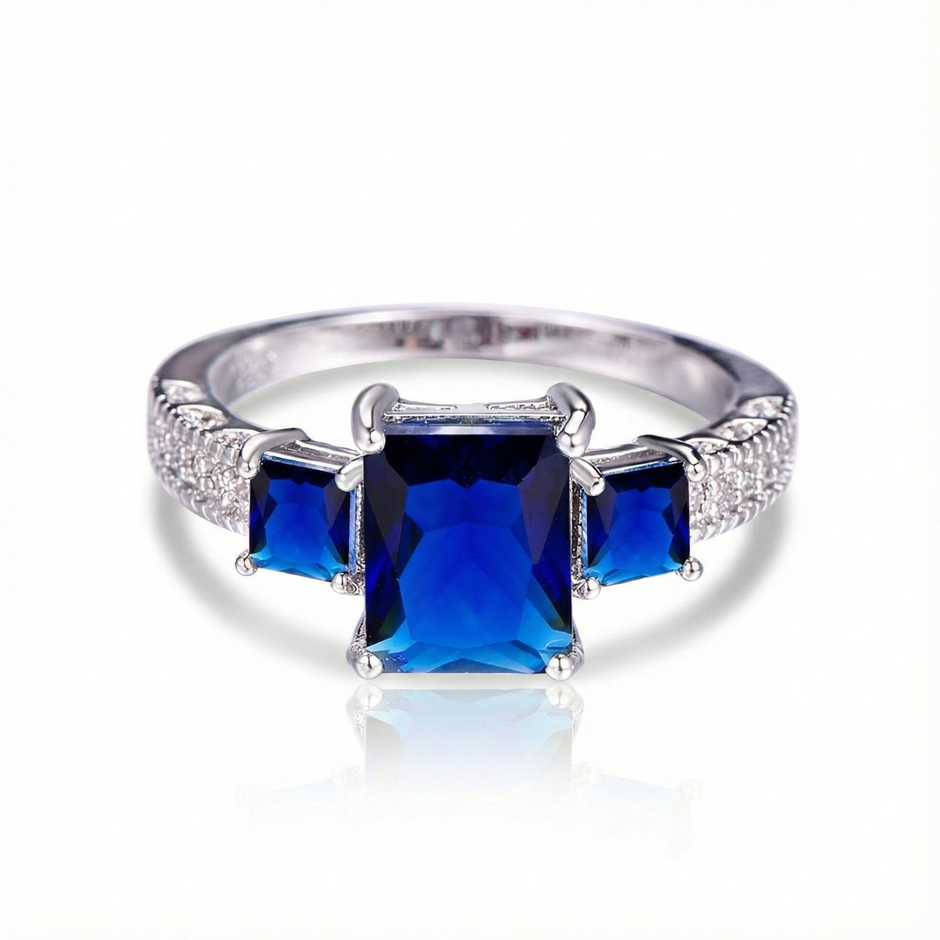 Silver ring with three blue gemstones on a white background