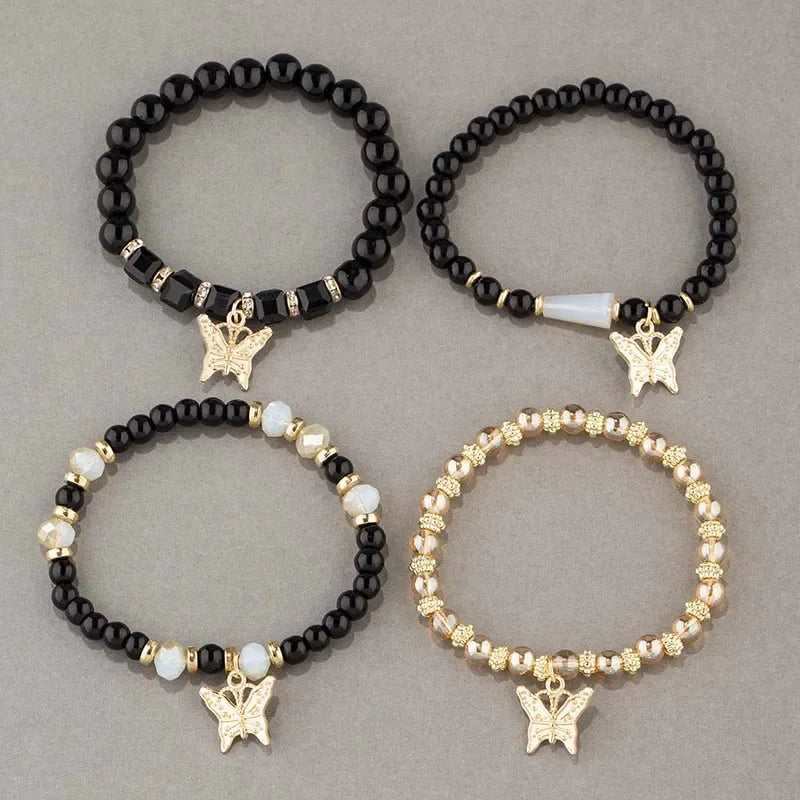 Four beaded bracelets with butterfly charms on a gray background